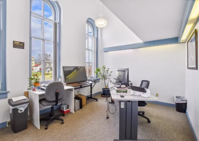 A large private office with big windows and a desk.