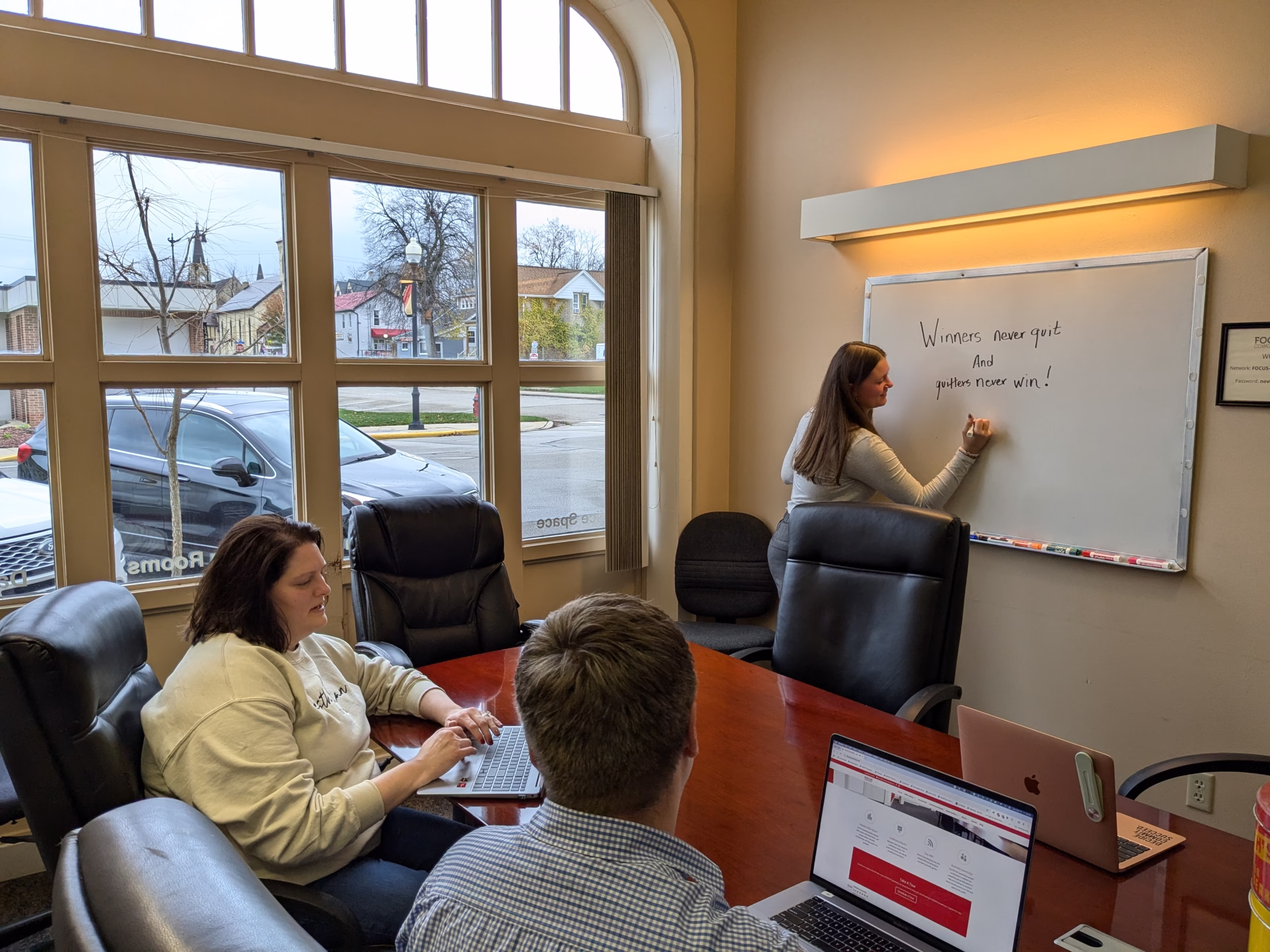 A woman writing on the whiteboard in the FOCUS Coworking conference room.